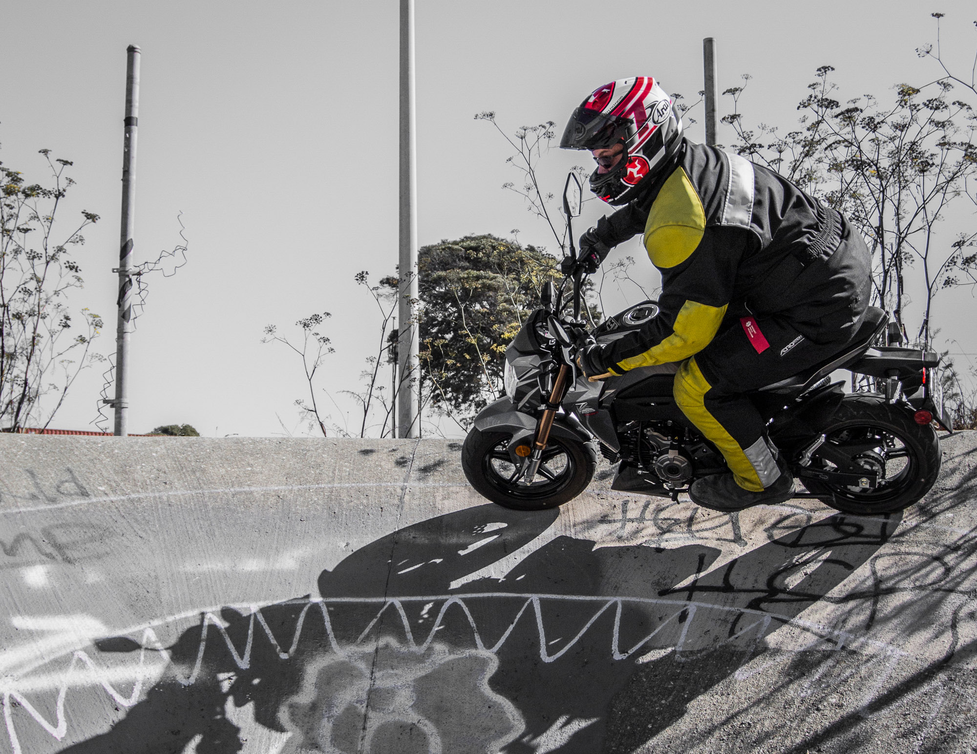 Surj Gish riding the wall of a secret spot on a Kawasaki Z125.
